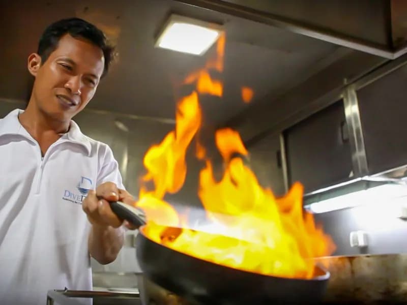 A cook prepares food aboard the Damai I Liveaboard