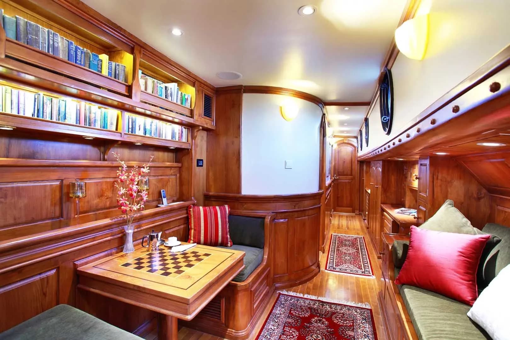 Interior of a luxury yacht featuring a chess board and shelves filled with books, showcasing elegance and leisure.