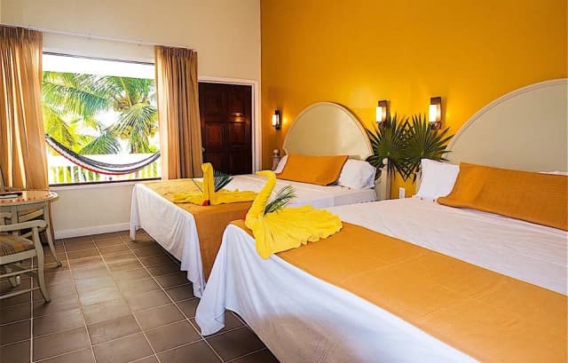 A bedroom with a view of greenery at Fantasy Island Roatan Resort.