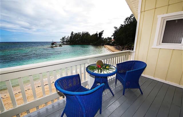 Chairs on a balcony overlook the beach and ocean at Fantasy Island Roatan Resort.