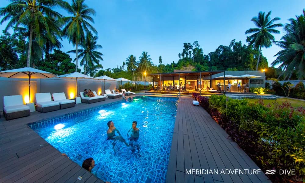 a swimming pool at dusk with swimmers at Meridian Adventure Dive Resort & Marina Club