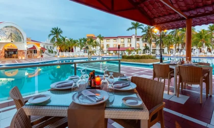 Outdoor poolside dining area with resort view and palm trees Outdoor poolside dining area with resort view and palm trees