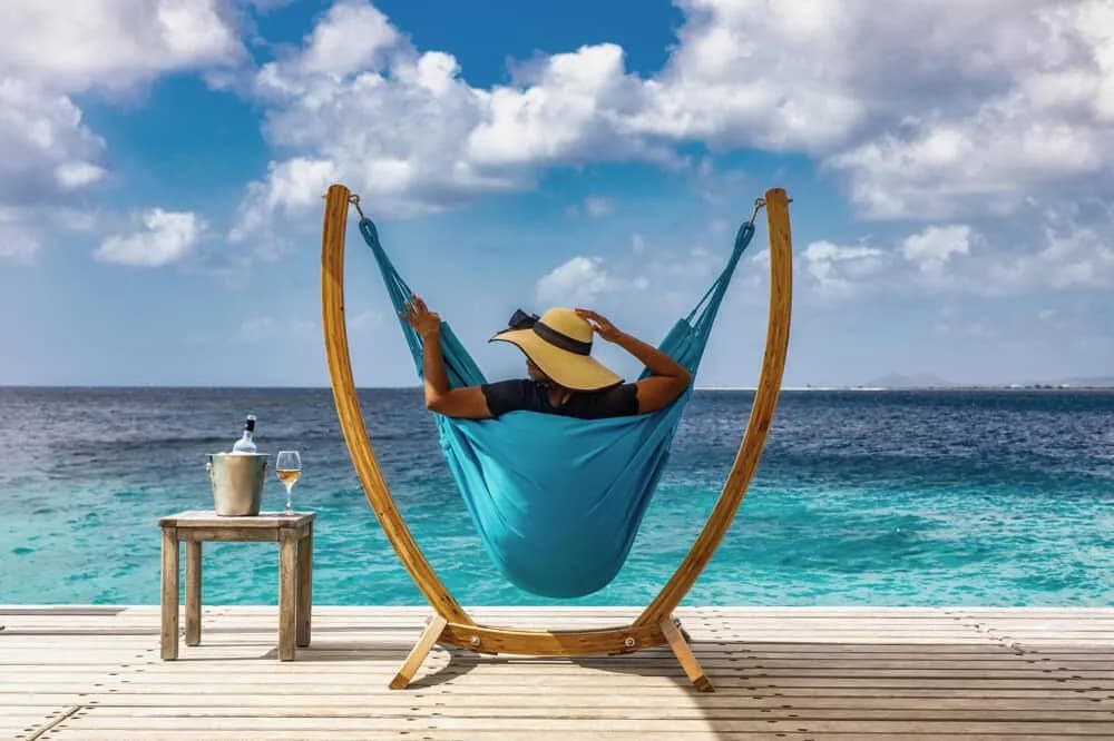 A guest relaxes in a hammock by the beach A guest relaxes in a hammock by the beach