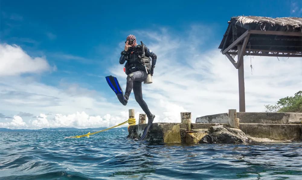 A scuba diver enters the water from Paradise Taveuni Resort