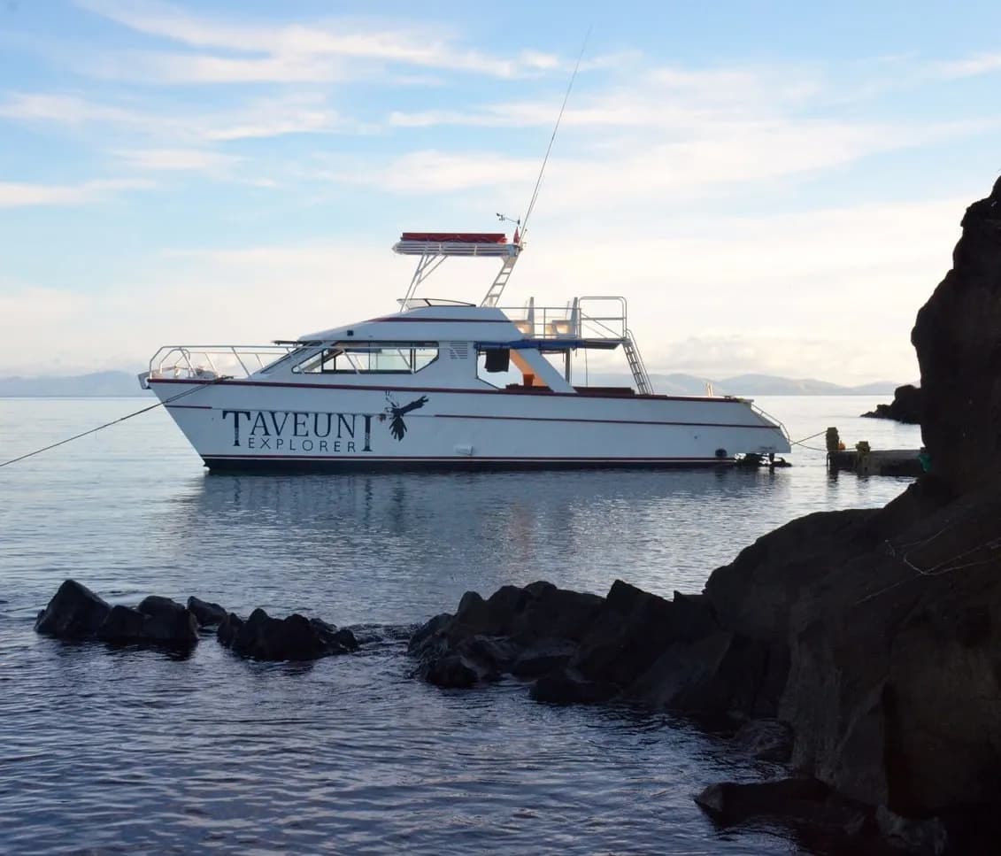A boat rests in the sea near some rocks