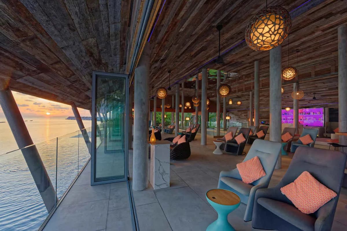 A lounge with pairs of chairs facing the sunset over the ocean at Kuramathi Island Resort Maldives. A lounge with pairs of chairs facing the sunset over the ocean at Kuramathi Island Resort Maldives.