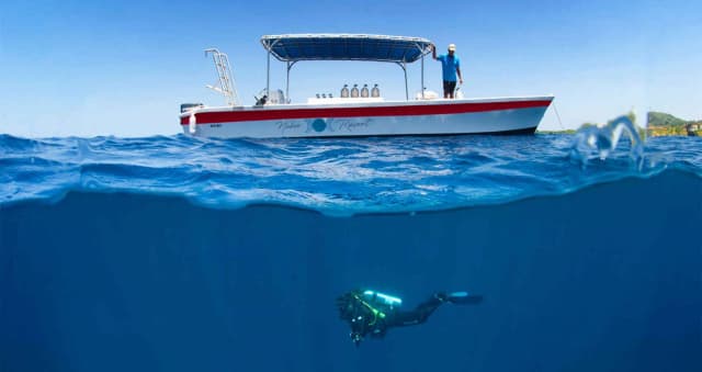 Scuba diver below a dinghy at Naboo Resort & Dive Center.