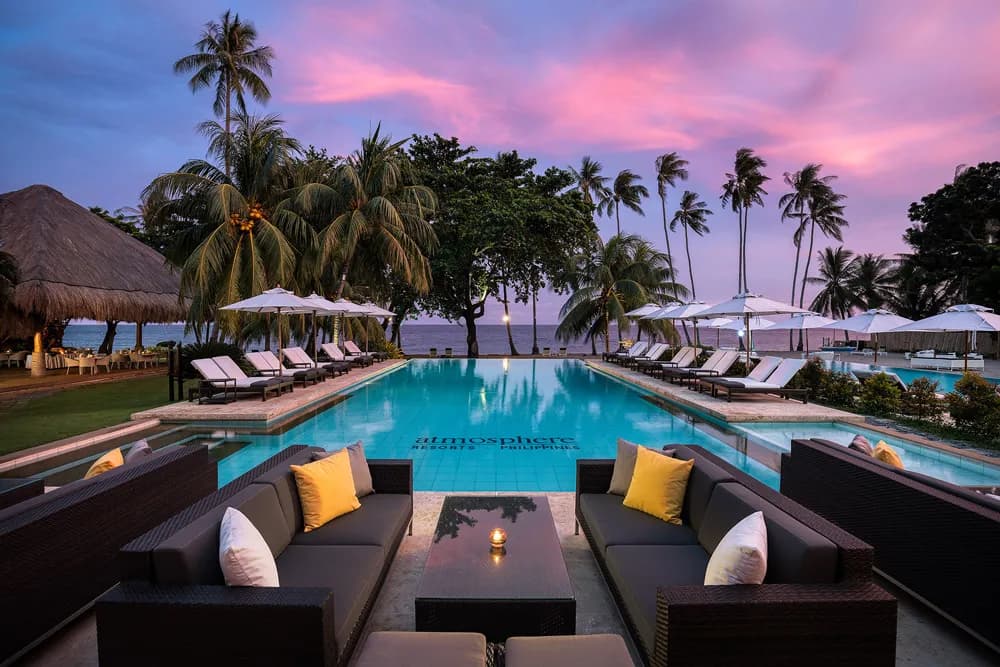 A pool lit at dusk with lounge chairs at Atmosphere Resort. A pool lit at dusk with lounge chairs at Atmosphere Resort.