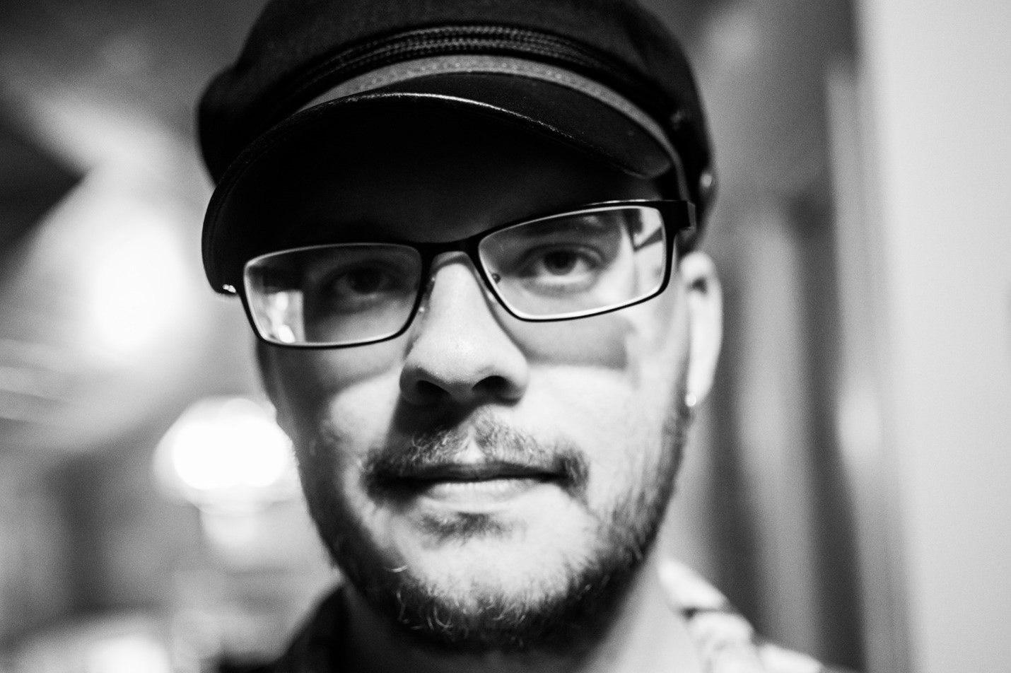 A headshot of a man wearing glasses and a hat.
