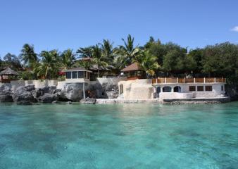 A view of Magic Island Dive Resort with clear turquoise sea in front.