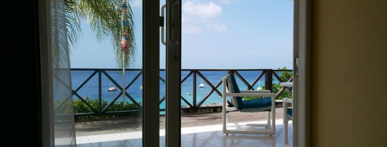 A door opens to a balcony overlooking the pristine sea.