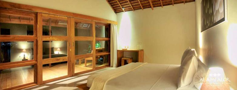 An elegant bedroom with glass doors at Alami Alor resort.