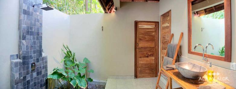 A partially-covered outdoor bathroom with shower and sink at Alami Alor resort.