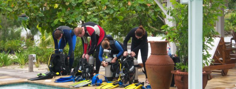 Scuba divers assemble equipment next to a pool