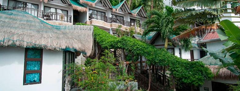 A picturesque room with a thatched roof and a path leading to it, located at Crystal Blue Resort in Anilao, Philippines.