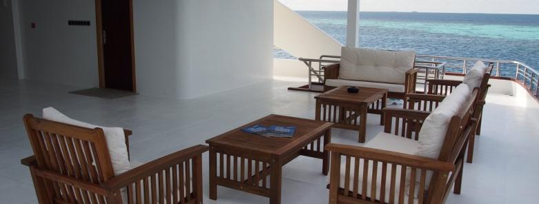 Deck of MV Emperor Serenity Liveaboard boat with furniture, offering a stunning ocean view in the Maldives.
