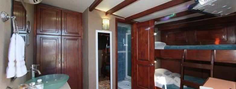 Interior of the MV Valentina twin cabin with two bunks, TV, chest, vanity, closet, and shower.