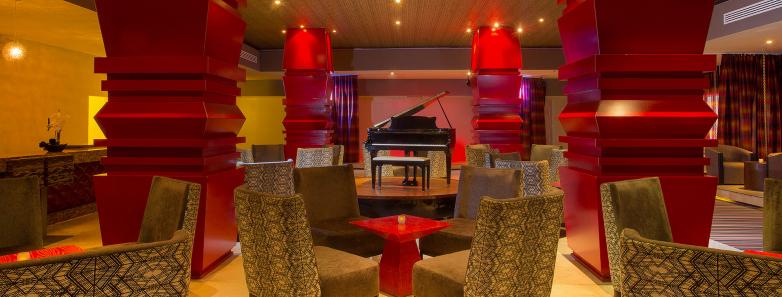 A piano sits at the center of tables and chairs in Luna Lounge at Playacar Palace.