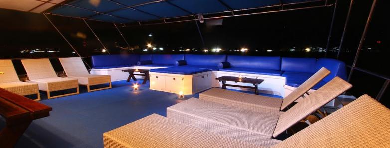 A nighttime view of the outdoor lounge with couches and sunbeds