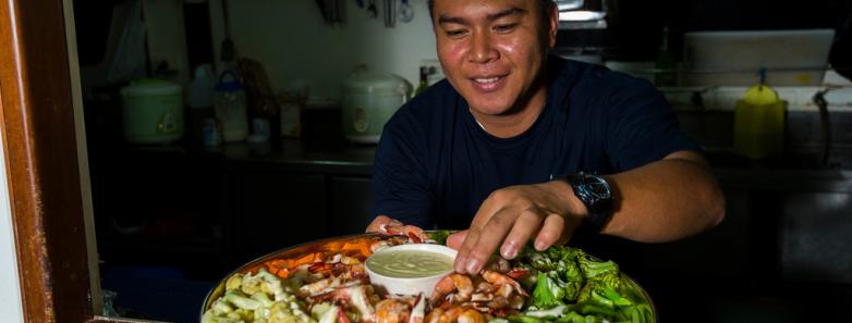 A chef presents a platter of seafood and vegetables