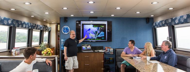 People observe a dive briefing aboard the Roatan Aggressor Liveaboard.