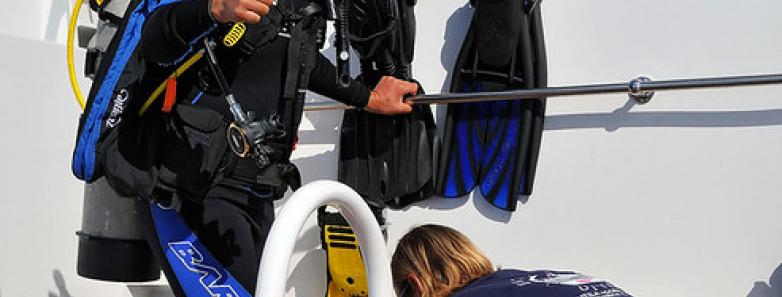 A scuba diver prepares to enter the water from the Roatan Aggressor Liveaboard.