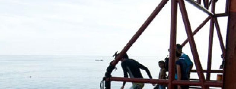 A person prepares to jump into the water from a platform on Seaventures Dive Rig.