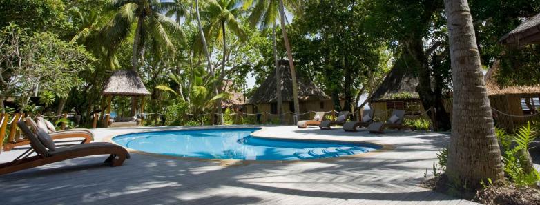 A swimming pool with lounge chairs at Toberua Island Resort Fiji.