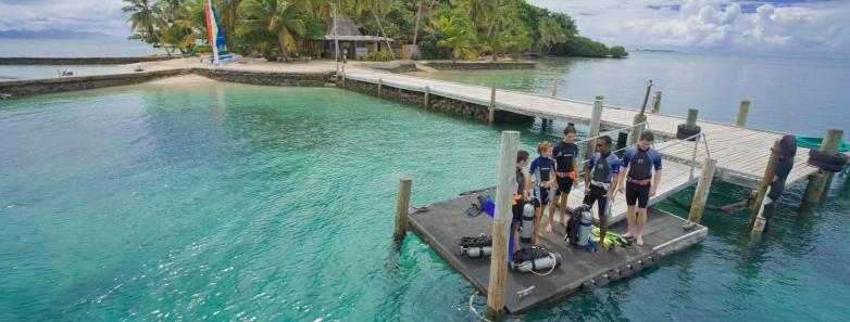 Scuba divers prepare to enter the water from the jetty at Toberua Island Resort Fiji.