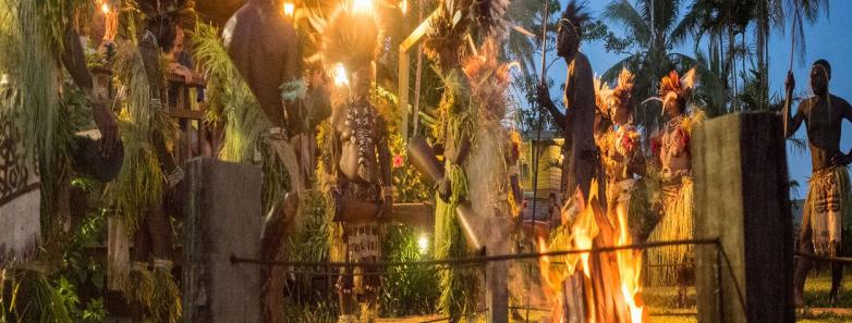 People gather in traditional clothing around a fire at Tufi Resort Papua New Guinea