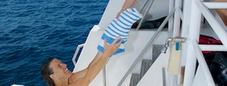 A crew member hands a towel to a guest aboard the Turks & Caicos Aggressor II