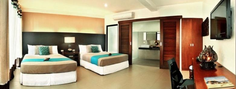A room with two beds, desk, chair, and TV at Aiyanar Beach & Dive Resort