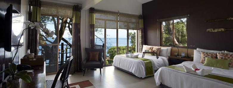 A suite at Aiyanar Beach & Dive Resort containing two beds with an ocean view.
