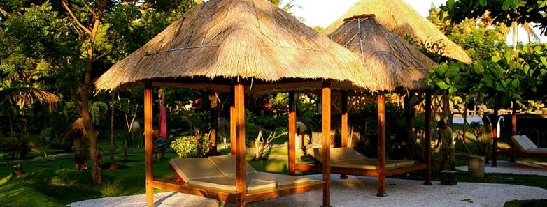 Covered lounge chairs in the garden at Alam Batu Beach Bungalow Resort Bali