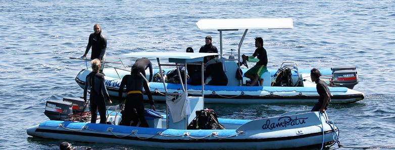 Scuba divers prepare to enter the water from the dive boats at Alam Batu Beach Bungalow Resort Bali