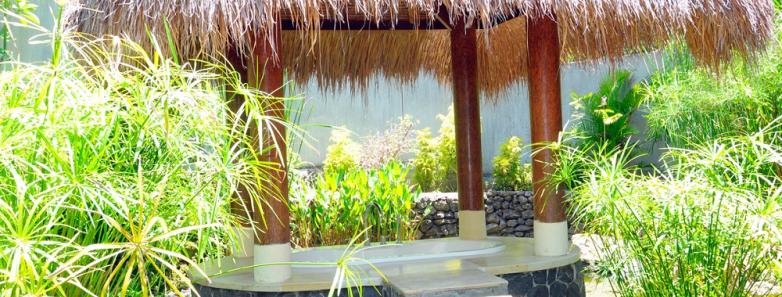 A platform with a sunken bathtub surrounded by a pond at Alam Batu Beach Bungalow Resort Bali
