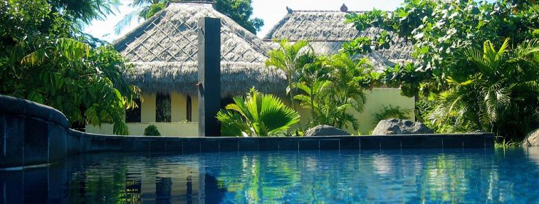 A pool with buildings in the background at Alam Batu Beach Bungalow Resort Bali