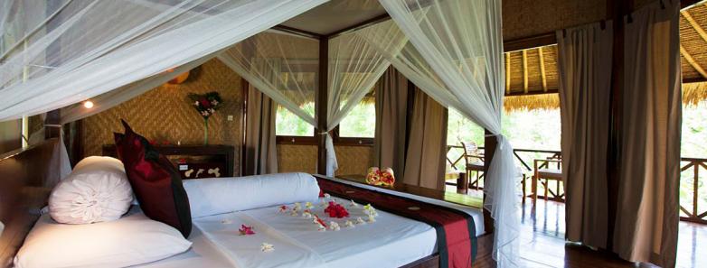 A tastefully decorated bungalow with a large bed at Alam Batu Beach Bungalow Resort Bali