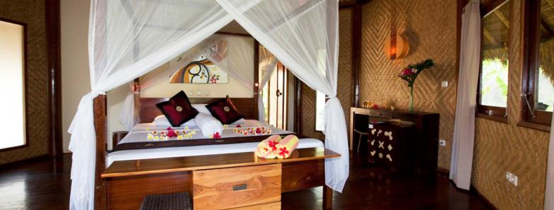 A large bed with a mosquito net in a bungalow at Alam Batu Beach Bungalow Resort Bali