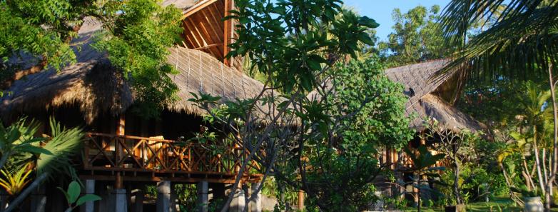A bungalow is nestled among lush foliage at Alam Batu Beach Bungalow Resort Bali