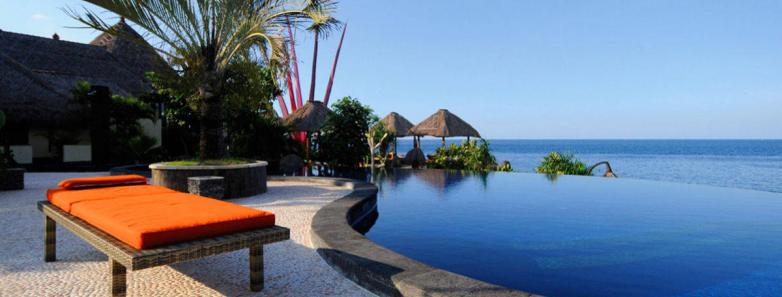 A lounge chair next to the infinity pool looking over the ocean at Alam Batu Beach Bungalow Resort Bali