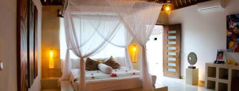 A bed sits on a raised platform in Villa Anton at Alam Batu Beach Bungalow Resort Bali