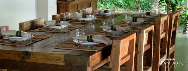 A wooden dining table set for mealtime at Alami Alor resort.