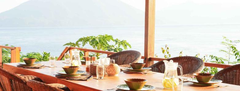 A table set for a meal with a volcano in the background at Alor Tanapi Dive Resort.