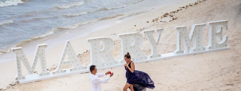A person proposes marriage to another person on the beach at Barcelo Maya Grand