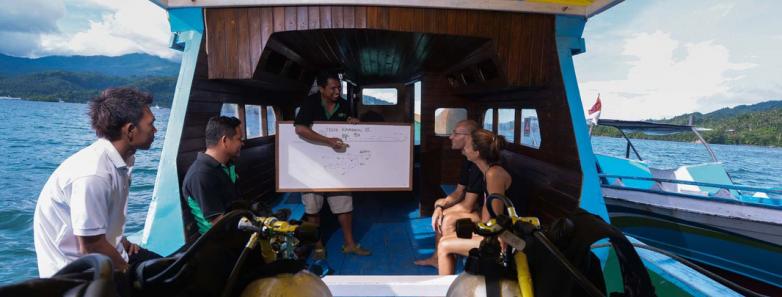 A guide gives a dive briefing on a boat at Bastianos Dive Resort Lembeh