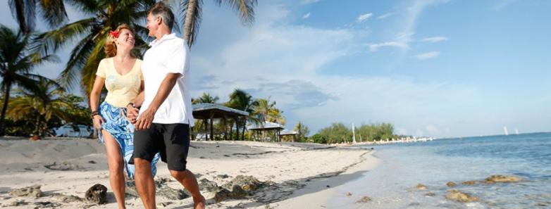 A couple strolls along the beach at Cayman Brac Beach Resort