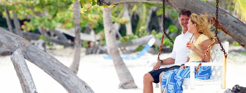 A couple sit on a swinging bench at Cayman Brac Beach Resort