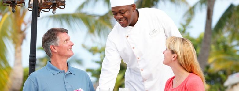 A chef serves two people a meal at Cayman Brac Beach Resort