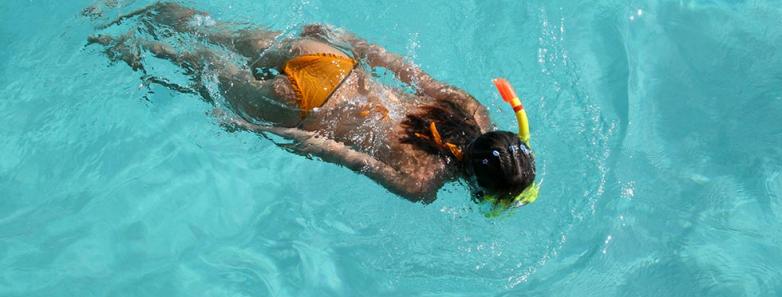 A woman snorkels in crystal clear water in Anilao, Philippines.